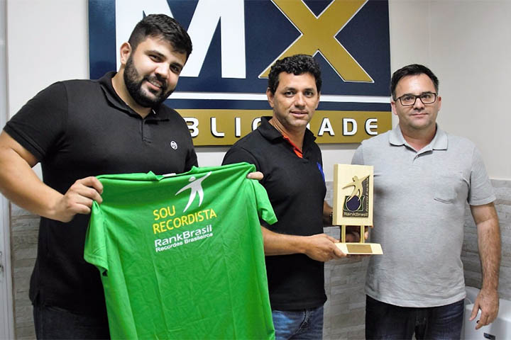 O diretor da MX, Allan Carvalho (à esquerda da foto) recebem com o acionista da empresa, Marcelo Viana (ao centro), das mãos de Luciano Cadari, da RankBrasil, o troféu pelo recorde do outdoor de 650m².